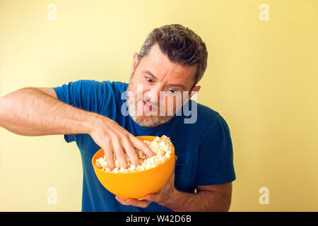 Porträt einer lustigen Mann essen Popcorn auf gelbem Hintergrund Stockfoto