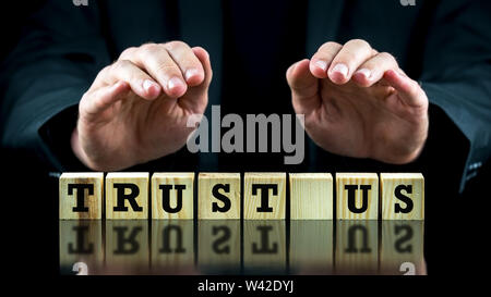 Konzeptionelle Bild mit Worten Vertrauen uns auf Holzblöcken oder Würfel durch die Hand eines Mannes, der Sie schützenden von oben geschützt. Stockfoto