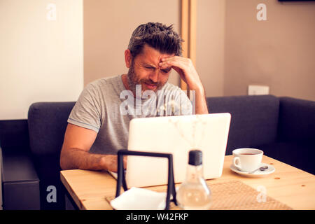 Mann mit einem Kopfschmerzen vor dem Laptop. Menschen, Gesundheit und Technologie Konzept Stockfoto