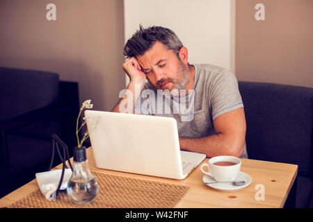 Mann mit einem Kopfschmerzen vor dem Laptop. Menschen, Gesundheit und Technologie Konzept Stockfoto