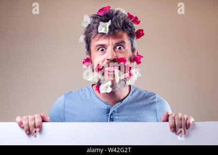 Schön überrascht Mann mit Blumen auf seinen Bart und Haar. Menschen, Gefühle, Sommer oder Frühling Konzept Stockfoto