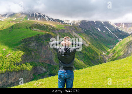 Ein Mann bewundert die schöne Landschaft in den Bergen, der Blick von der Rückseite Stockfoto