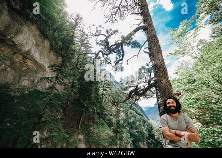 Lächelnden jungen Mann in einem Wald in die Kamera schaut Stockfoto