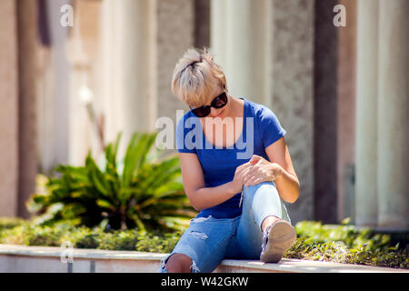 Junge Frau mit Knieschmerzen während Outdoor wandern. Gesundheit, Medizin, Personen Konzept Stockfoto