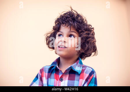 Kleiner Junge mit lockigem Haar Denken über etwas. Kinder und Emotionen Konzept Stockfoto