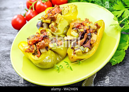 Paprika gefüllt mit Pilzen, Tomaten, Zucchini, Auberginen, Zwiebeln, gewürzt mit Wein, Knoblauch, Thymian und Gewürze in einem grünen Platte gegen da Stockfoto