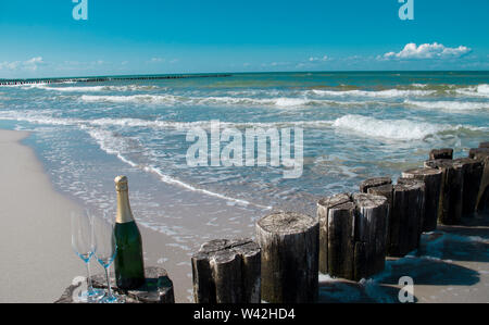 Eine Flasche Champagner am Strand gebaut, weißem Sand und blauem Meer ist ein Urlaub im Paradies. Stockfoto