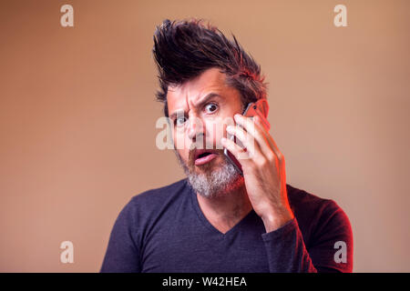 Bärtiger Mann denken und die Suche nach einem auf seine smart phone Chat. Menschen, Emotionen und Technik Konzept Stockfoto