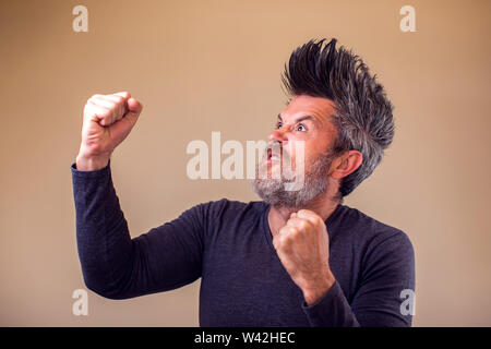 Closeup Portrait eines zornigen erwachsenen Mann mit Bart und Irokesen zeigt Faust. Menschen und Emotionen Konzept Stockfoto