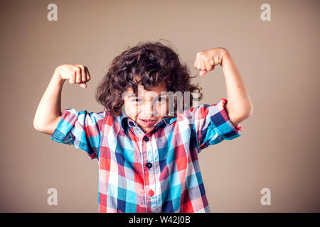 Porträt einer starken Kid zeigt die Muskeln seiner Arme auf grauem Hintergrund Stockfoto