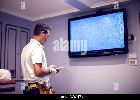 Ein Mann Arbeitnehmer fix tv mit blauen Bildschirm "No Signal". Stockfoto