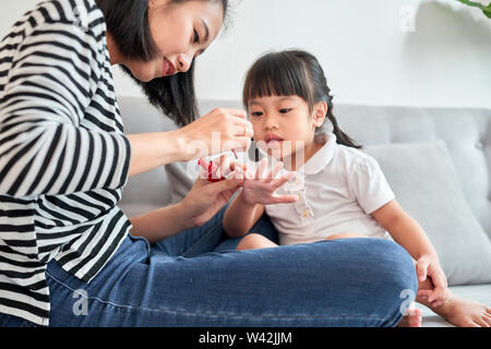 Schöne junge Mutter ist die Lackierung der Nagellack zu Ihrem süßen kleinen Tochter Stockfoto