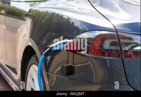 Aufladen der Batterie Elektrofahrzeug. EV Kraftstoff Plug-in Hybrid auto Nähe zu sehen. Stockfoto