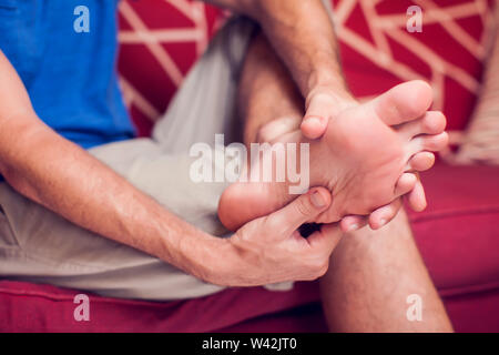 Mann fühlt starke Schmerzen im Fuß zu Hause. Leute, Medizin und healtcare Konzept Stockfoto