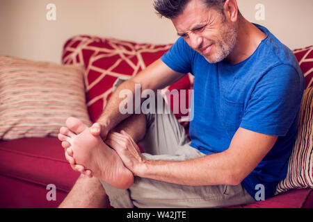 Mann fühlt starke Schmerzen im Fuß zu Hause. Leute, Medizin und healtcare Konzept Stockfoto