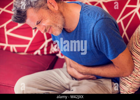 Mann fühlt sich starke Magenschmerzen zu Hause. Menschen, Gesundheitswesen und Medizin Konzept Stockfoto