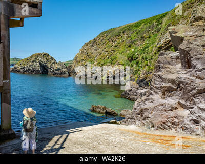 Eine Dame in einem Strohhut auf Ramsey Sound aus der St. Justinian Hafen auf der Pembrokeshire Coast, South Wales Stockfoto