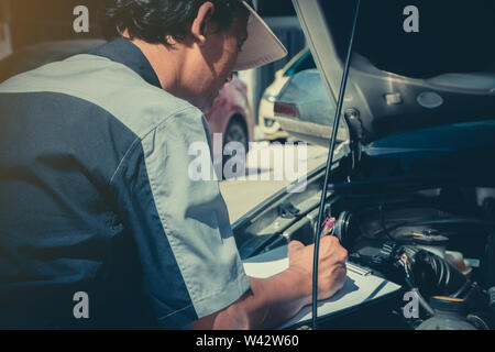 Professionelle Auto Reparatur Techniker überprüfen Sie den Motor gemäß der Checkliste Dokumente, um sicherzustellen, dass sie sich nach dem Standard geprüft Stockfoto