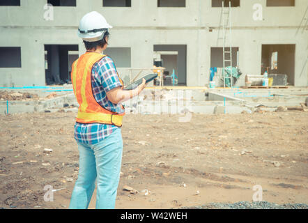 Asiatische Frauen Arbeiter und Techniker über die Verwendung von Tablet für die Überprüfung der Genauigkeit in den Plätzen vor dem Gebäude und Häuser. Stockfoto