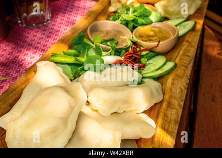 Wareniki, vareniki, polnische Pierogi, pyrohy oder Knödel auf dem Holzbrett mit grünem Salat, traditionelles Essen, Polen Stockfoto