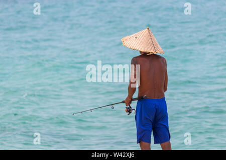 Koh Samui, Thailand - 19 April, 2019: Lokale Mann mit handgefertigten bamboo Hut angeln mit einem Fisch Pole Stockfoto