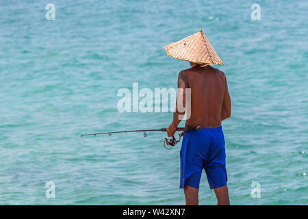 Koh Samui, Thailand - 19 April, 2019: Lokale Mann mit handgefertigten bamboo Hut angeln mit einem Fisch Pole Stockfoto