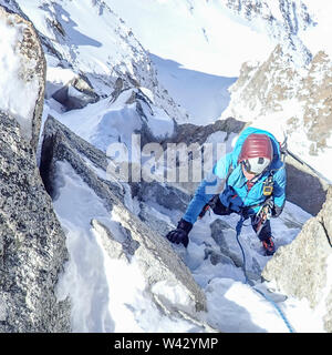 Eine Frau Bergsteiger klettert eine steile Rinne gemischt auf der Cosmiques Arete Stockfoto