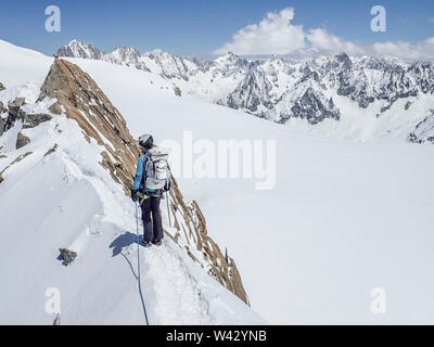 Eine Frau Bergsteiger blickt zurück von einem exponierten Snow Ridge in den Alpen Stockfoto