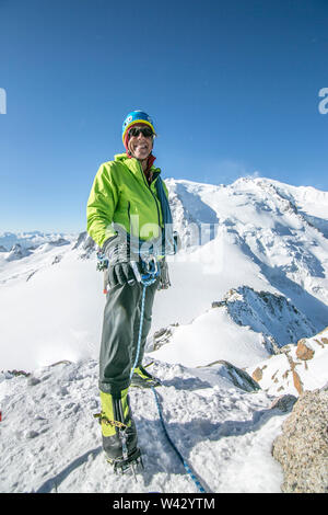 Ein lächelndes Alpinist in seinen Fünfzigern steht auf einem Schnee Vorgebirge Stockfoto