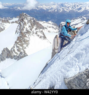 Eine Frau alpinist lächelt, während an einem steilen Hang hoch oben gemischt Stockfoto