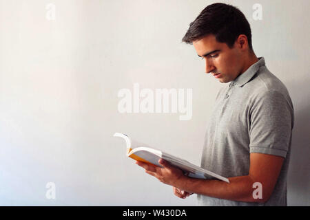 Mann verkleidet in Grau mit einem Buch zu Hause. Stockfoto