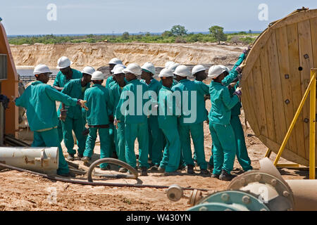 Bergbau, Verwaltung und Transport von Titanmineralsanden. Instandhaltungsteam verlegt neue Stromkabel an der Seite des Bergbauteichs für die Nassanlage dahinter. Stockfoto