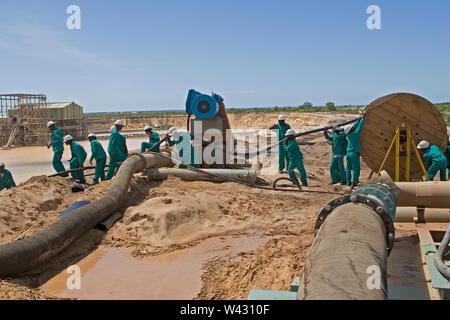 Bergbau, Verwaltung und Transport von Titanmineralsanden. Instandhaltungsteam verlegt neue Stromkabel an der Seite des Bergbauteichs für die Nassanlage dahinter. Stockfoto