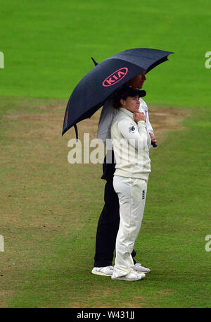 Englands Tammy Beaumont und 3 Schiedsrichter Paul Baldwin Tierheim nehmen unter einem Regenschirm am Tag Zwei der Frauen Asche Test Match an der Cooper Associates County, Taunton. Stockfoto