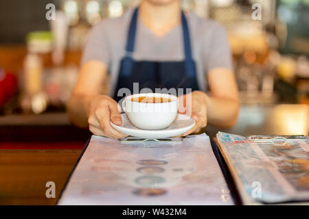 Kellnerin Kaffee beim Stehen in der Coffee Shop Zähler dienen. Stockfoto