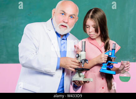 Chemische Industrie. Reifen Lehrer der Biologie. Schüler Mädchen in der Schule lab. Kleines Mädchen mit Mann tutor Chemie. Verwenden Sie die Lupe. Wissenschaft Klassenzimmer. Die Mikroskopie. Laborgeräte. Stockfoto