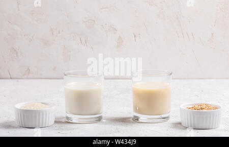 Gläser mit gesunden Reis und Hafermilch, Schüsseln mit Reis Saatgut und Haferflocken auf weißem Hintergrund. Kostenlose Milch Konzept Lactose. Bild mit kopieren. Stockfoto