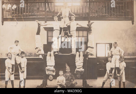 Jahrgang 1907 Photographische Postkarte zeigt eine britische Gruppe von hauptsächlich Kind Akrobaten/Turnerinnen und Turner, die in einer Halle. Stockfoto