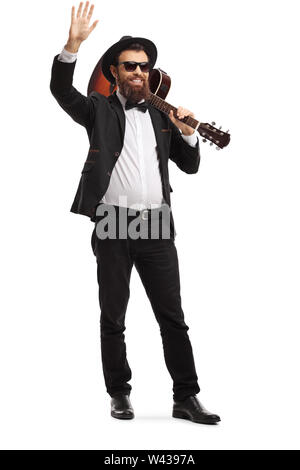 In voller Länge Porträt einer männlichen Musiker winken mit einer akustischen Gitarre auf seiner Schulter auf weißem Hintergrund Stockfoto