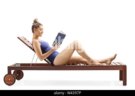 Volle Länge geschossen von einer jungen Frau, ein Buch lesen und entspannen auf einer Liege auf weißem Hintergrund Stockfoto