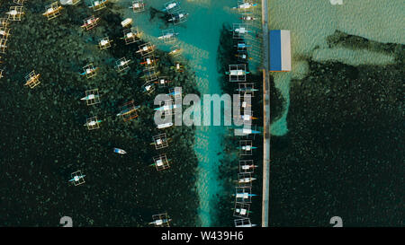 Draufsicht: Boote warten auf Touristen und die Pier in der Stadt General Luna auf der Insel Siargao. Stockfoto