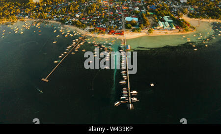 Stadt Allgemeine Luna an der Küste von Siargao mit einem Pier, ein Hafen und touristische Boote bei Sonnenaufgang, Luftbild. Sommer und Reisen Urlaub Konzept. Stockfoto