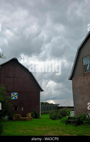 Unwetter und Dunkle, bedrohliche Gewitterwolken Swirl über einen kleinen Hof und Scheune und Nebengebäude und Bäume, Sturm, in Wisconsin, USA. Stockfoto