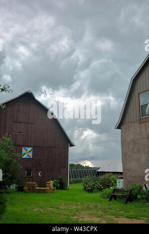 Unwetter und Dunkle, bedrohliche Gewitterwolken Swirl über einen kleinen Hof und Scheune und Nebengebäude und Bäume, Sturm, in Wisconsin, USA. Stockfoto