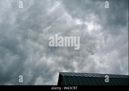 Unwetter und Dunkle, bedrohliche Gewitterwolken Swirl über einen kleinen Hof und Scheune und Nebengebäude und Bäume, Sturm, in Wisconsin, USA. Stockfoto