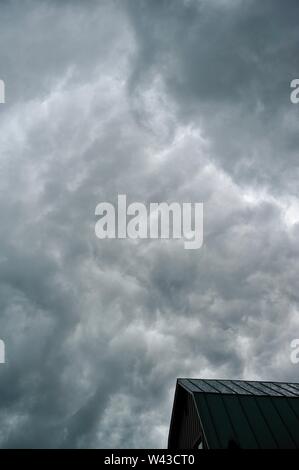 Unwetter und Dunkle, bedrohliche Gewitterwolken Swirl über einen kleinen Hof und Scheune und Nebengebäude und Bäume, Sturm, in Wisconsin, USA. Stockfoto