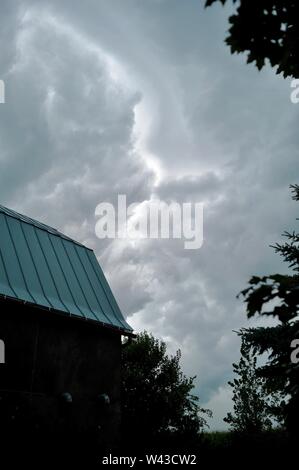 Unwetter und Dunkle, bedrohliche Gewitterwolken Swirl über einen kleinen Hof und Scheune und Nebengebäude und Bäume, Sturm, in Wisconsin, USA. Stockfoto