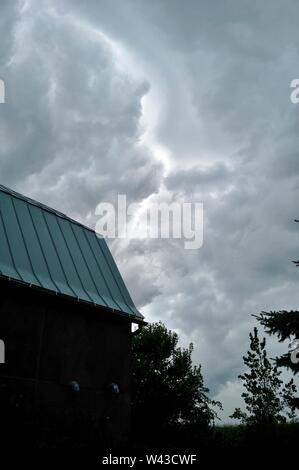 Unwetter und Dunkle, bedrohliche Gewitterwolken Swirl über einen kleinen Hof und Scheune und Nebengebäude und Bäume, Sturm, in Wisconsin, USA. Stockfoto