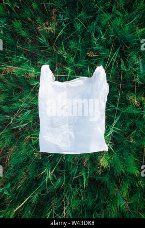 Plastikbeutel im grünen Gras, Natur Umweltverschmutzung Konzept. Stück Kunststoff Papierkorb (leer essen Paket) weggeworfen auf einem Rasen Stockfoto