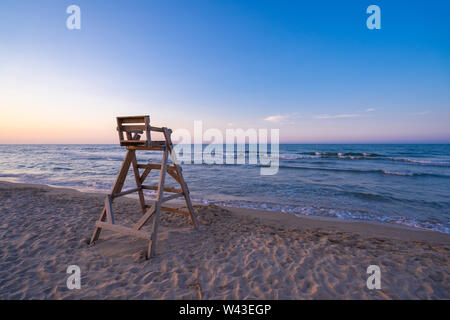 Strand mit Holz- Rettungsschwimmer Stuhl im Sonnenuntergang. Stockfoto